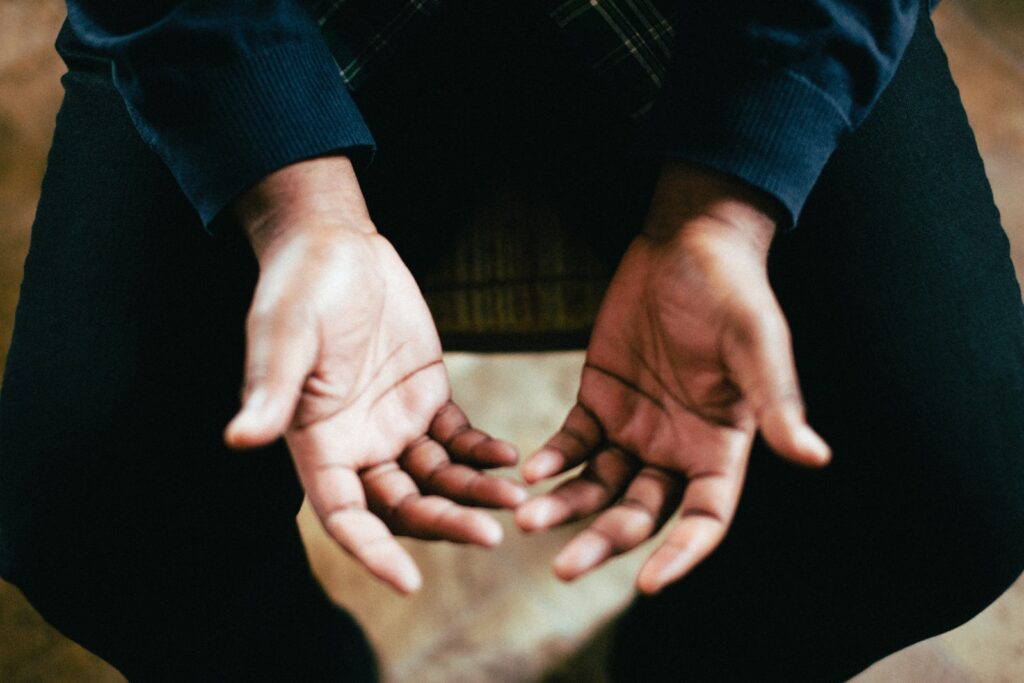 person showing both palms while sitting on chair and praying through the process